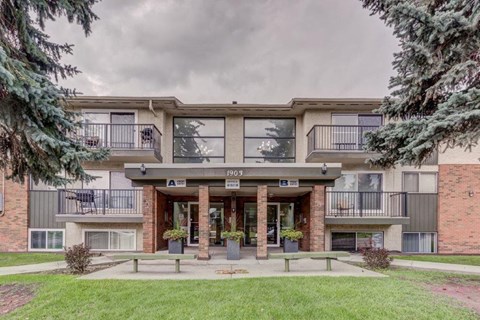 a building with two balconies and a lawn in front of it